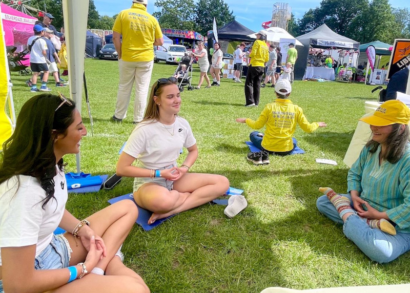Image for article Público aprende os exercícios do Falun Dafa durante festividade em Surrey, Reino Unido